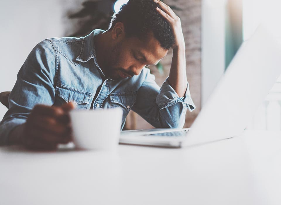 A man working through paperwork at a laptop